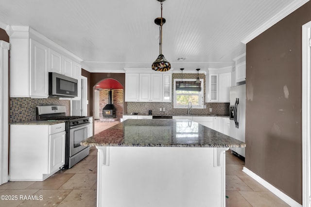 kitchen featuring a kitchen island, appliances with stainless steel finishes, dark stone countertops, white cabinetry, and backsplash