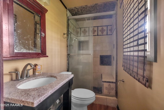 bathroom featuring vanity, toilet, a shower stall, and wood finished floors
