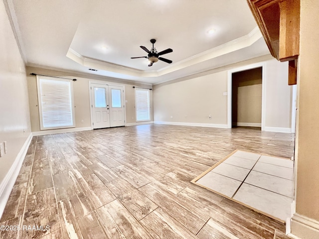 unfurnished living room with crown molding, hardwood / wood-style floors, ceiling fan, and a tray ceiling