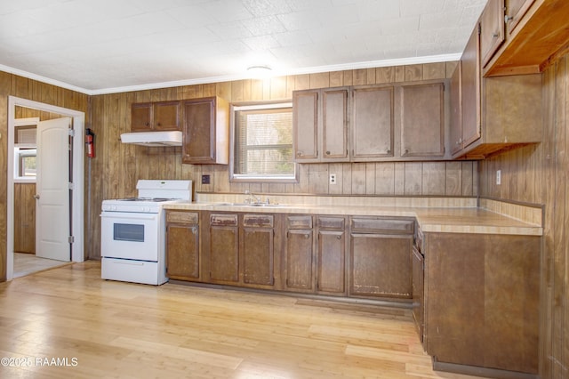 kitchen featuring ornamental molding, wood walls, light hardwood / wood-style floors, and white gas range oven