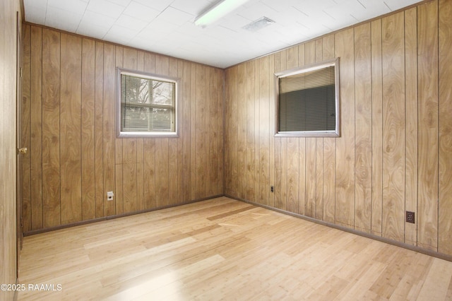 spare room with wood walls and light hardwood / wood-style flooring