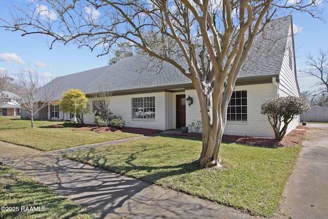 ranch-style home featuring brick siding, a front lawn, and a shingled roof