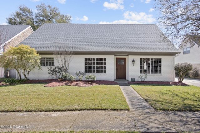 view of front of property featuring brick siding, a shingled roof, and a front yard