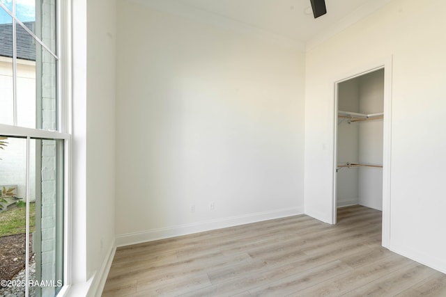 unfurnished bedroom featuring crown molding, light hardwood / wood-style floors, a closet, and a spacious closet