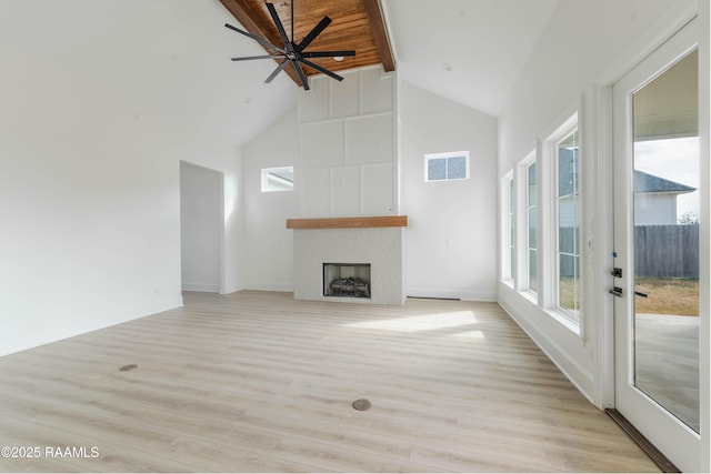 unfurnished living room with high vaulted ceiling, a fireplace, and light hardwood / wood-style floors