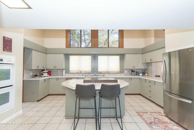 kitchen featuring light tile patterned floors, light countertops, white double oven, and freestanding refrigerator