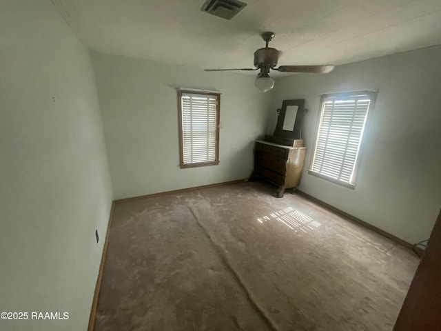 carpeted empty room with ceiling fan and a wealth of natural light