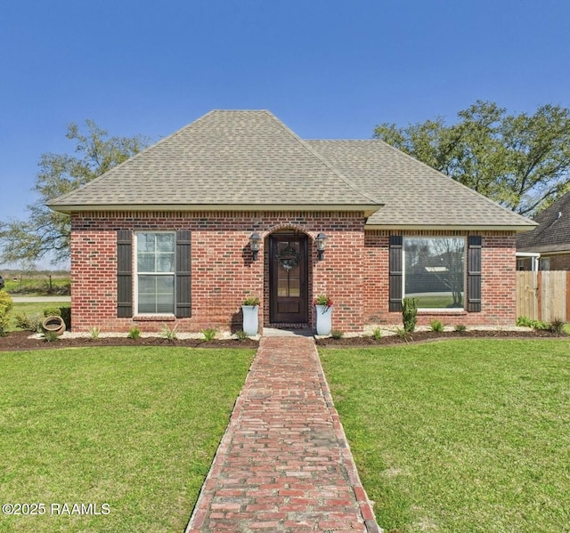 view of front facade featuring brick siding, a front lawn, and roof with shingles