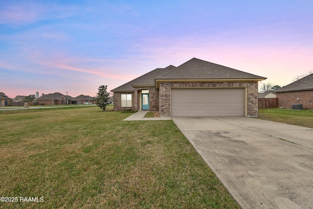 view of front of home featuring cooling unit, a garage, and a lawn