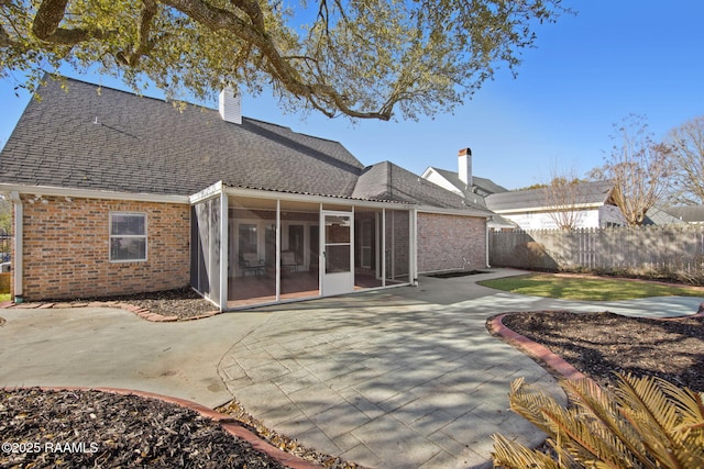 rear view of property with a patio, fence, brick siding, and a chimney