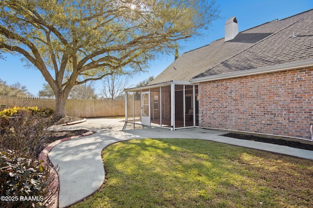 view of yard with a patio, fence, and a sunroom