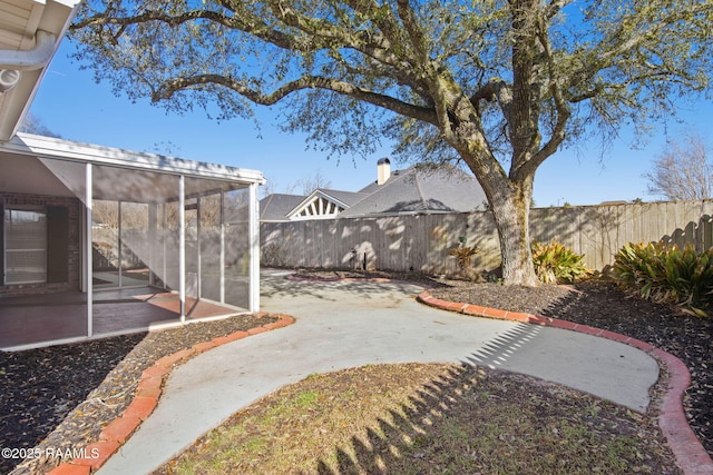 view of yard featuring a patio area, a fenced backyard, and a sunroom