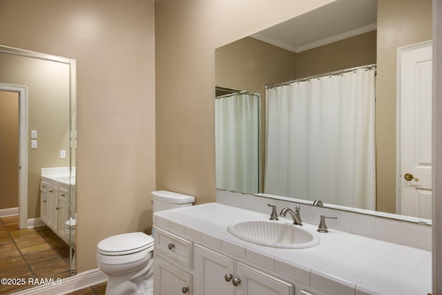 bathroom with vanity, crown molding, toilet, and baseboards