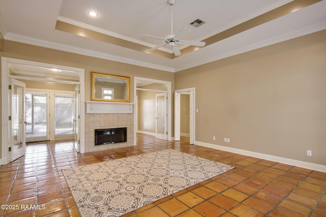 unfurnished living room featuring a ceiling fan, baseboards, ornamental molding, a tile fireplace, and a raised ceiling