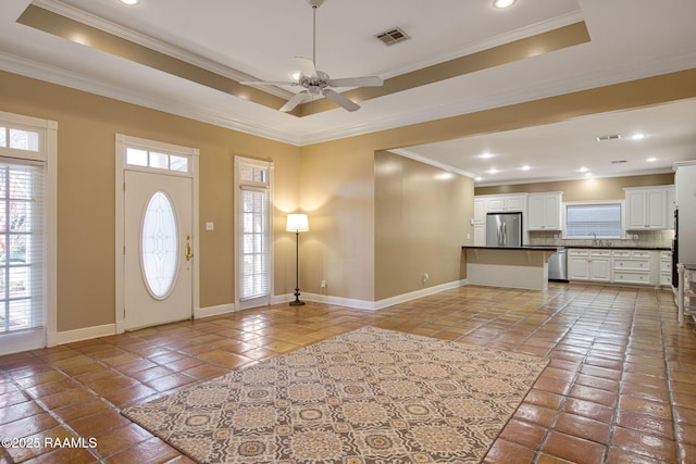 entryway featuring a tray ceiling, crown molding, visible vents, and baseboards