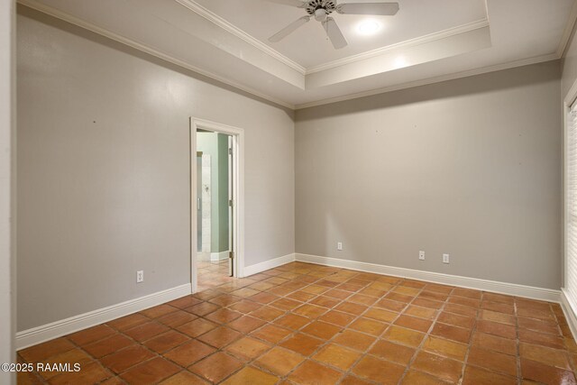 tiled empty room with a tray ceiling, a ceiling fan, baseboards, and ornamental molding