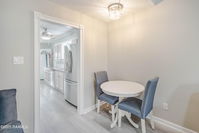 dining room with ceiling fan, a textured ceiling, and light hardwood / wood-style flooring