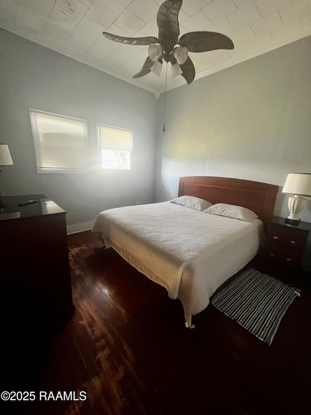 bedroom with crown molding, dark wood-type flooring, and ceiling fan