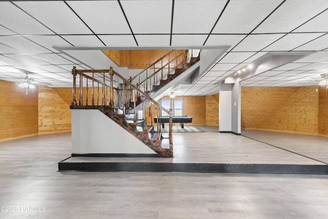 stairway with a drop ceiling, hardwood / wood-style flooring, and wooden walls