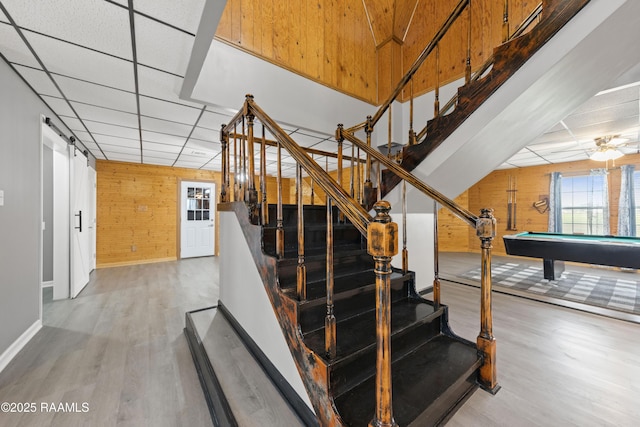 stairs featuring hardwood / wood-style flooring, billiards, a drop ceiling, and wood walls