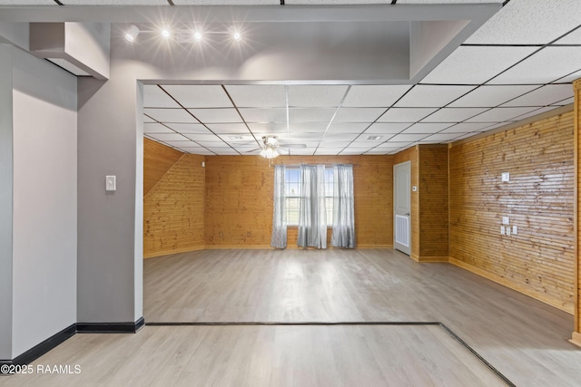 interior space featuring hardwood / wood-style flooring, a paneled ceiling, and brick wall