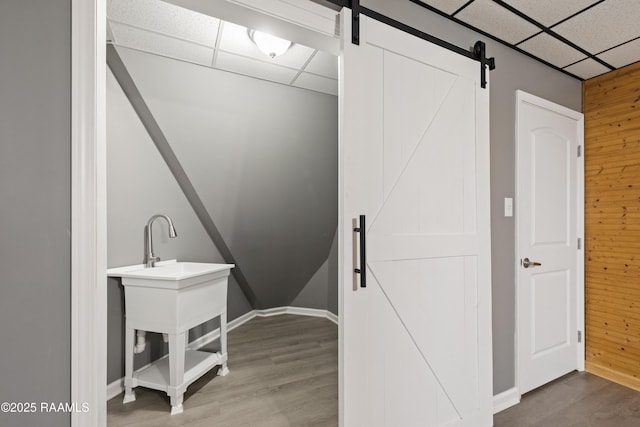 interior space featuring wooden walls, wood-type flooring, and a barn door