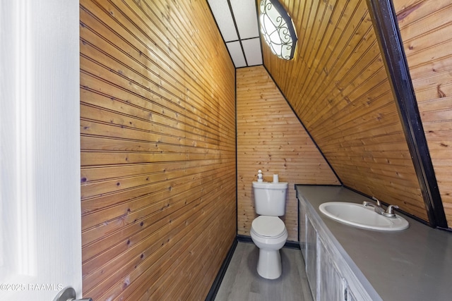 bathroom with wood ceiling, wooden walls, vanity, vaulted ceiling, and toilet