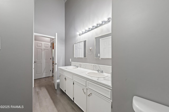 bathroom with a towering ceiling, vanity, toilet, and hardwood / wood-style floors