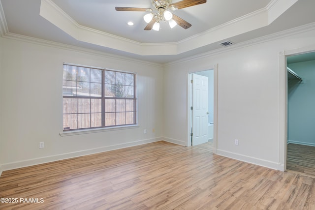 empty room featuring light hardwood / wood-style flooring, ornamental molding, a raised ceiling, and ceiling fan