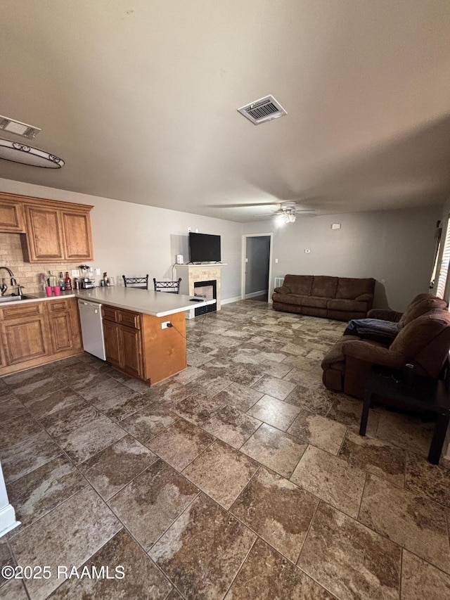 kitchen with kitchen peninsula, sink, decorative backsplash, ceiling fan, and white dishwasher