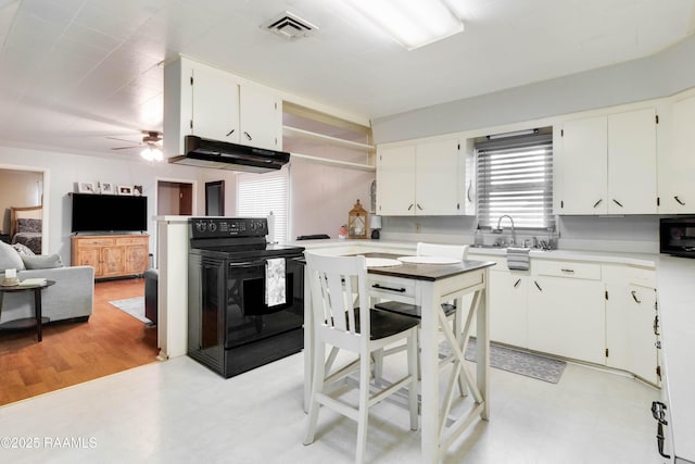 kitchen featuring light countertops, black range with electric stovetop, under cabinet range hood, and light floors