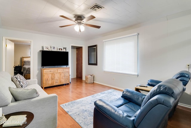 living area with a ceiling fan, baseboards, visible vents, and wood finished floors