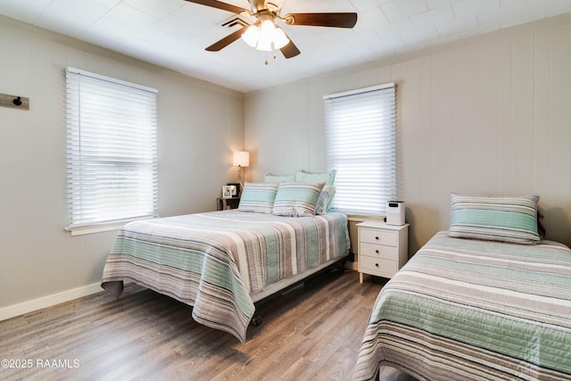 bedroom with a ceiling fan, baseboards, visible vents, and wood finished floors