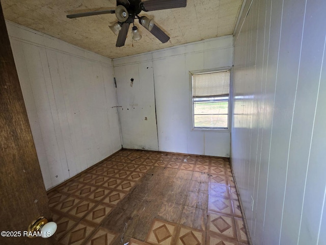 spare room featuring ceiling fan and wood walls