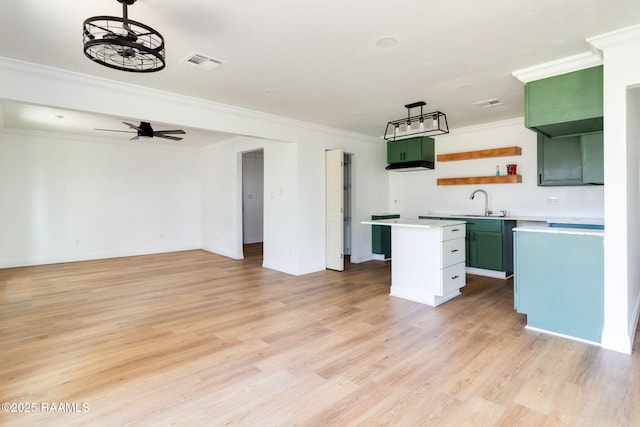 kitchen with crown molding, ceiling fan, a kitchen island, and light wood-type flooring