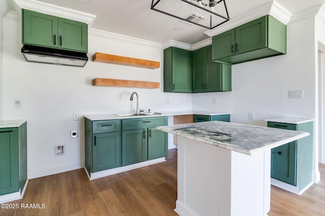 kitchen with sink, ornamental molding, green cabinetry, and a kitchen island