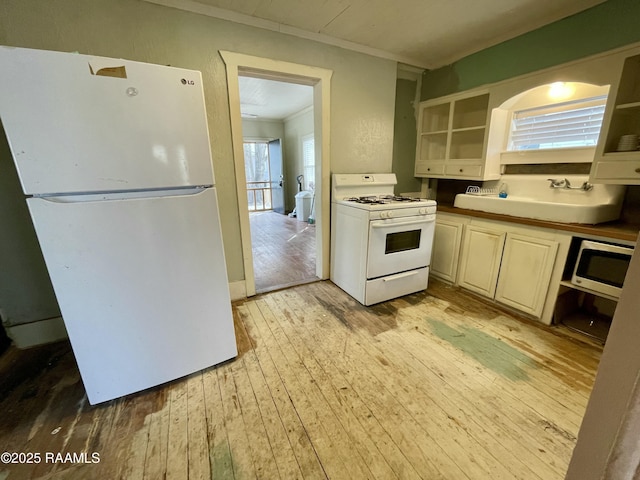 kitchen with white appliances, open shelves, a sink, light wood-style floors, and crown molding