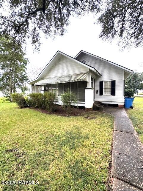 view of front of house featuring a sunroom and a front lawn