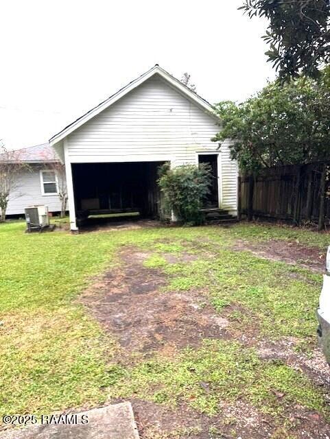 view of side of home with a garage, central AC unit, and a lawn