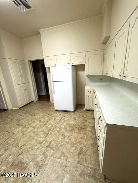 kitchen with white cabinetry, crown molding, and white fridge