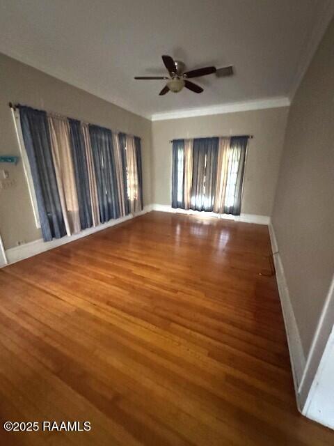 empty room with crown molding, wood-type flooring, and ceiling fan