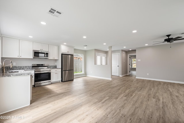 kitchen featuring sink, white cabinets, light stone counters, light hardwood / wood-style floors, and stainless steel appliances