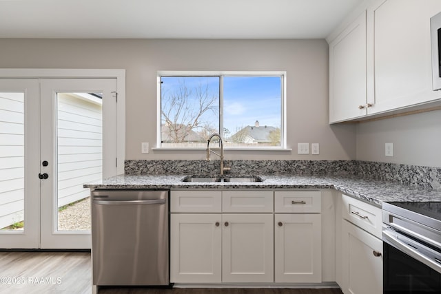 kitchen featuring french doors, sink, light stone counters, stainless steel dishwasher, and white cabinets