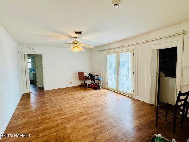 interior space with a ceiling fan, french doors, visible vents, and wood finished floors