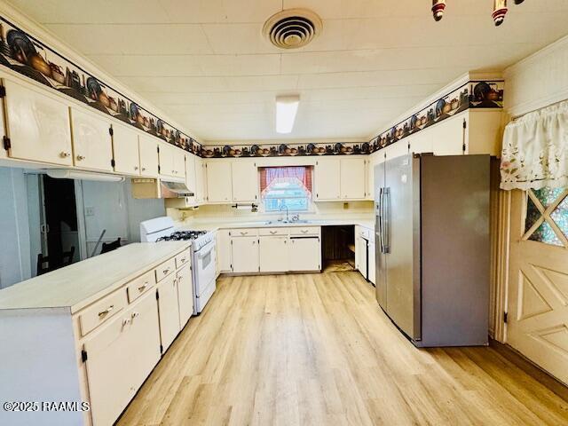 kitchen with gas range gas stove, light countertops, visible vents, light wood-type flooring, and stainless steel fridge with ice dispenser