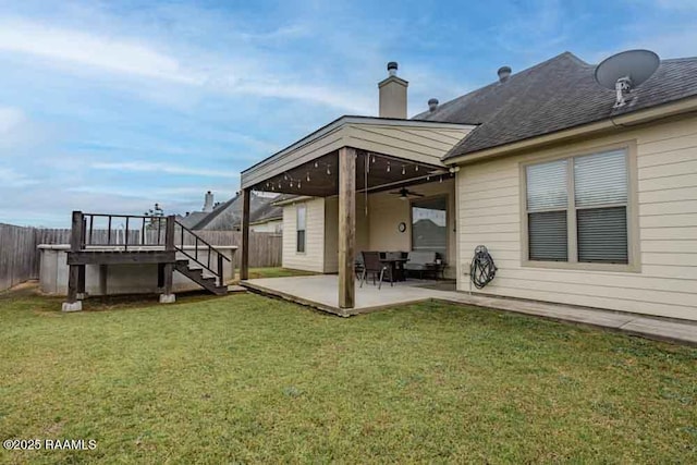 rear view of property featuring stairway, fence, a chimney, a patio area, and a lawn