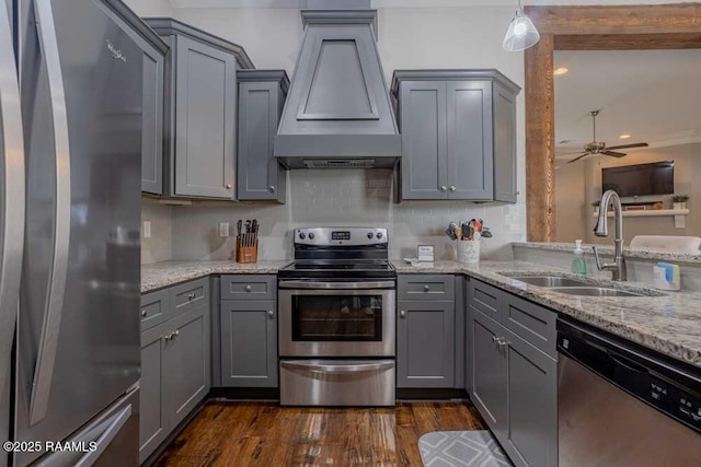 kitchen with a sink, appliances with stainless steel finishes, gray cabinetry, and custom range hood