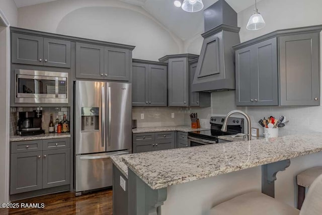 kitchen with light stone counters, a peninsula, gray cabinetry, stainless steel appliances, and vaulted ceiling