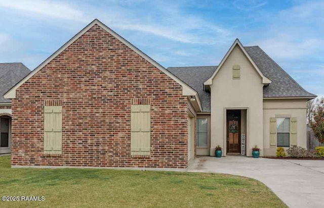 view of front of home featuring brick siding, a shingled roof, and a front lawn