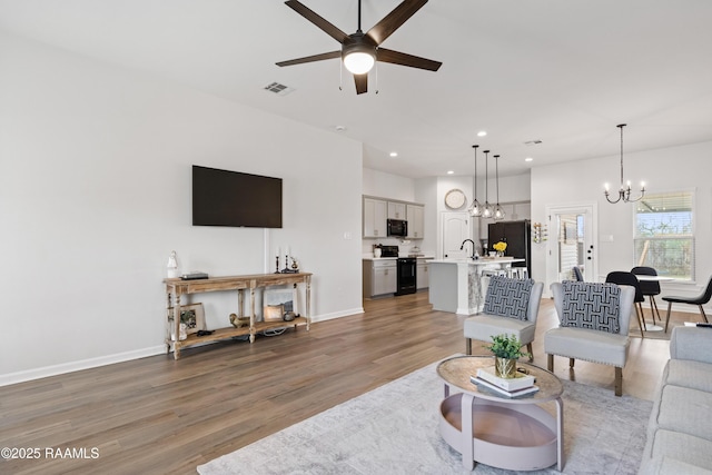 living room featuring hardwood / wood-style flooring and ceiling fan with notable chandelier